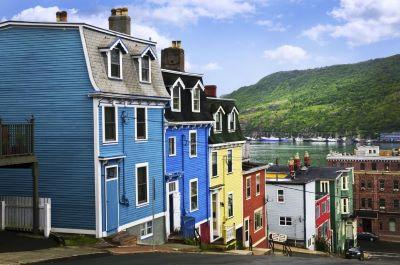 A row of colorful houses by a body of water

Description automatically generated